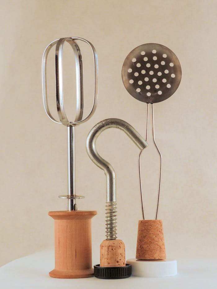 why-choose-us Artistic arrangement of kitchen utensils with corks and metal parts in a playful still life.